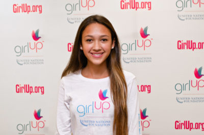 Alexa Brewster_2012-2013 Class Teen Advisors (close angle headshot, a picture little blurry ) a teen girl wearing her girl up white shirt with her smiley face facing the camera, and background is girlup.org board