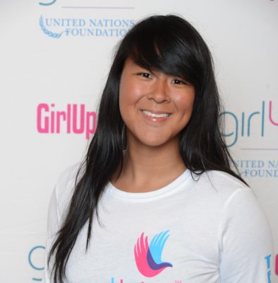 Amy Gong Liu_ 2014-2015 Teen Advisors (close angle headshot) a teen girl wearing her girl up white shirt with her smiley face facing the camera, and background is girlup.org board