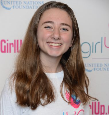 Anna McGuire_ 2014-2015 Teen Advisors (close angle headshot) a teen girl wearing her girl up white shirt with her smiley face facing the camera, and background is girlup.org board