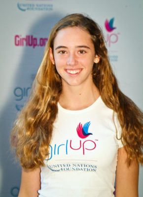 Annie Kiyonga Hometown: Chevy Chase, MD._2011-2012 Class The second class of Teen Advisors (close angle headshot) a teen girl wearing her girl up white shirt with her smiley face facing the camera, and background is girlup.org board