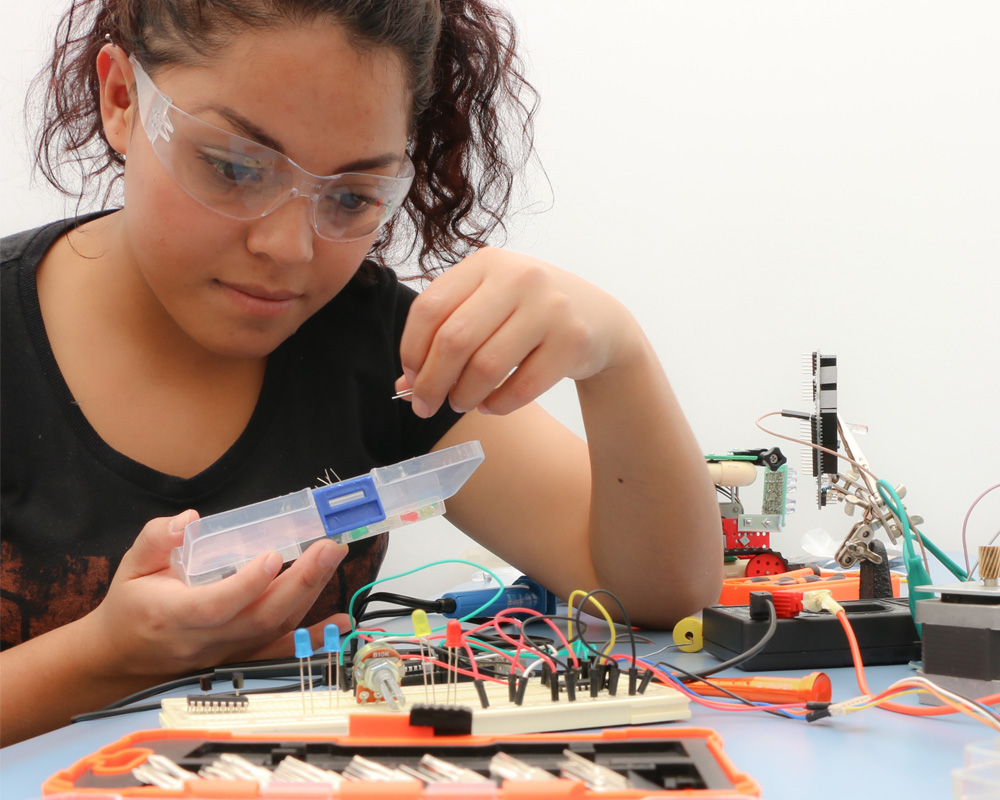 a girl wearing lab glasses and testing electricity on the table
