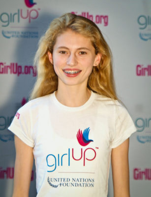 Avery McCall Hometown: Winnetka, IL._2011-2012 Class The second class of Teen Advisors (close angle headshot) a teen girl wearing her girl up white shirt with her smiley face facing the camera, and background is girlup.org board