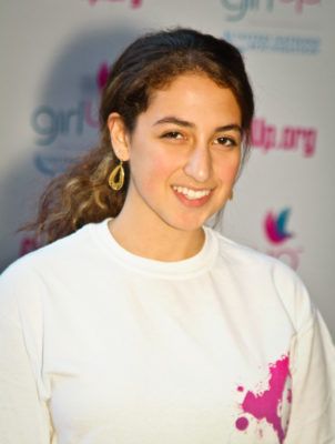 Eliora Katz Hometown: Washington, D.C._2011-2012 Class The second class of Teen Advisors (close angle headshot) a teen girl wearing her girl up white shirt with her smiley face facing the camera, and background is girlup.org board