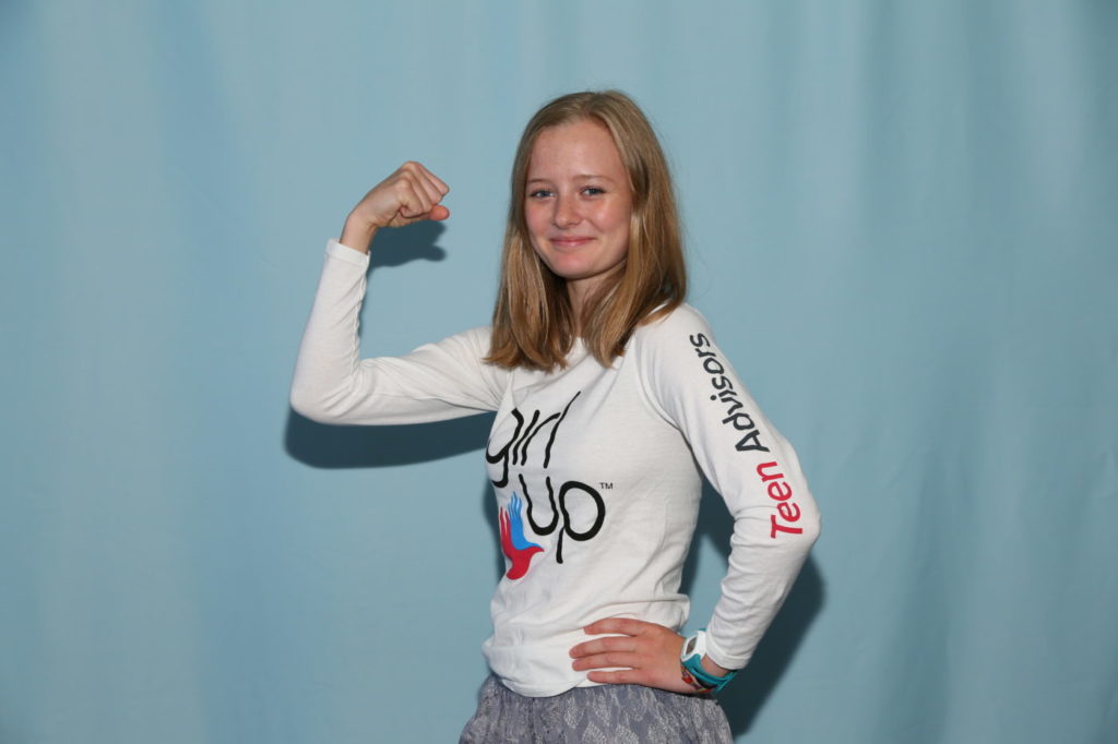 Eva teen advisor (wearing Girl Up shirt) pose the superwoman pose for the summit (back group is blue)