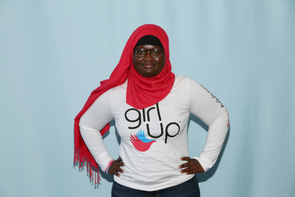 Fatimata teen advisor (girl up shirt) pose the superwoman pose for the summit picture (blue backgroup)