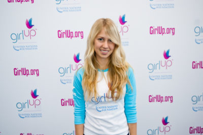 Hadley Walsh_The founding class of Teen Advisors(close angle, but not clear picture headshot ) a teen girl wearing her girl up blue long shirt with her smiley face facing the camera, and background is girlup.org board