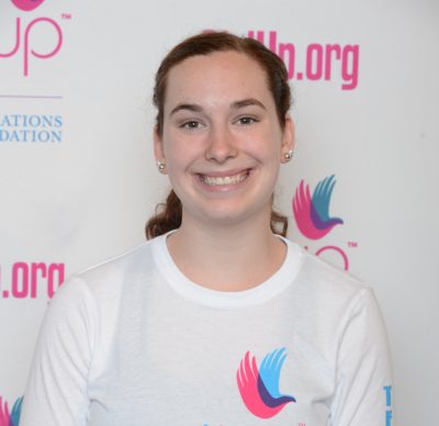 Hayley Peacock_ 2014-2015 Teen Advisors (close angle headshot) a teen girl wearing her girl up white shirt with her smiley face facing the camera, and background is girlup.org board