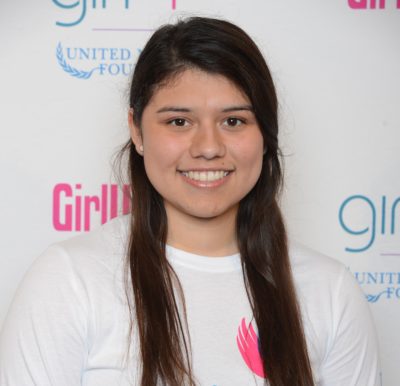 Janet Diaz_ 2014-2015 Teen Advisors (close angle headshot) a teen girl wearing her girl up white shirt with her smiley face facing the camera, and background is girlup.org board
