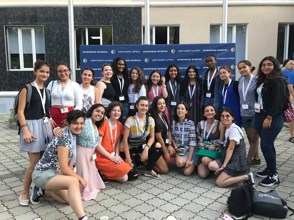 a group picture of girl up girls in front of the WiSci event board