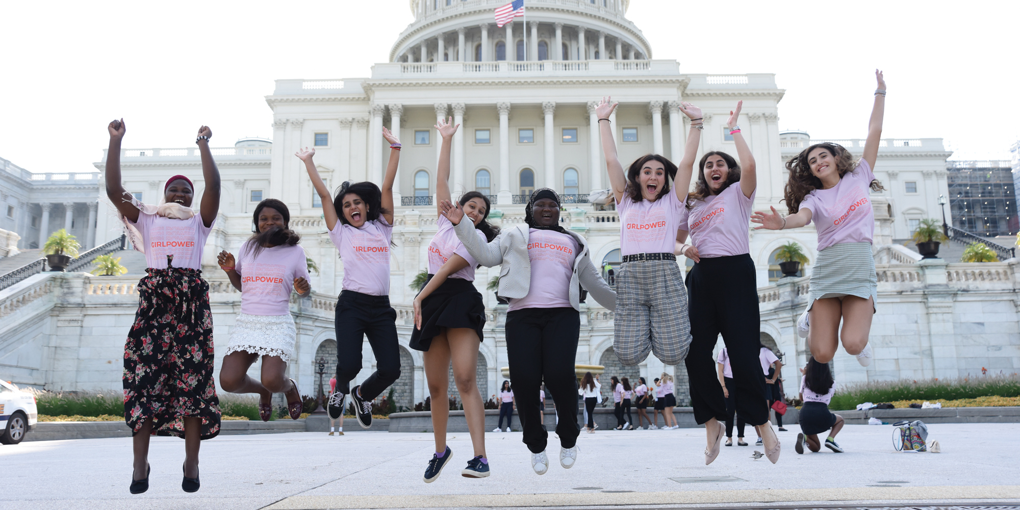 full angle shot of a group of Girl Up girls with a different ethnic group do a jumping picture in front of the capitol in DC