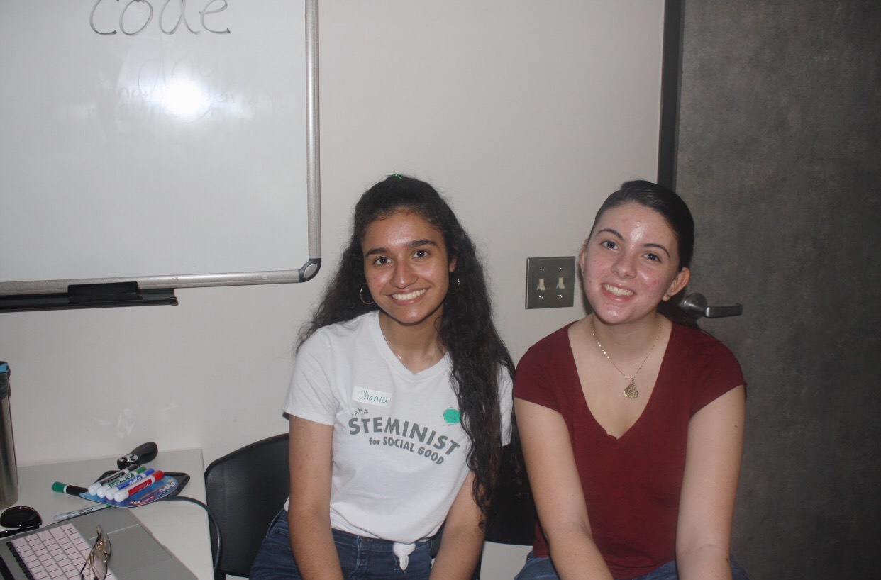 two girls picture with "steminist" shirt in front of the white broad