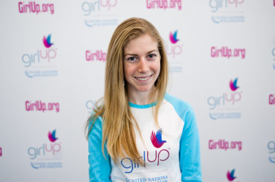 Shannon McNamara,The founding class of Teen Advisors(close angle, but not clear picture headshot ) a teen girl wearing her girl up blue long shirt with her smiley face facing the camera, and background is girlup.org board