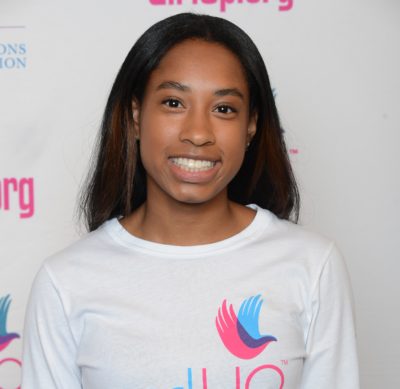 Simone Cowan_ 2014-2015 Teen Advisors (close angle headshot ) a teen girl wearing her girl up white shirt with her smiley face facing the camera, and background is girlup.org board