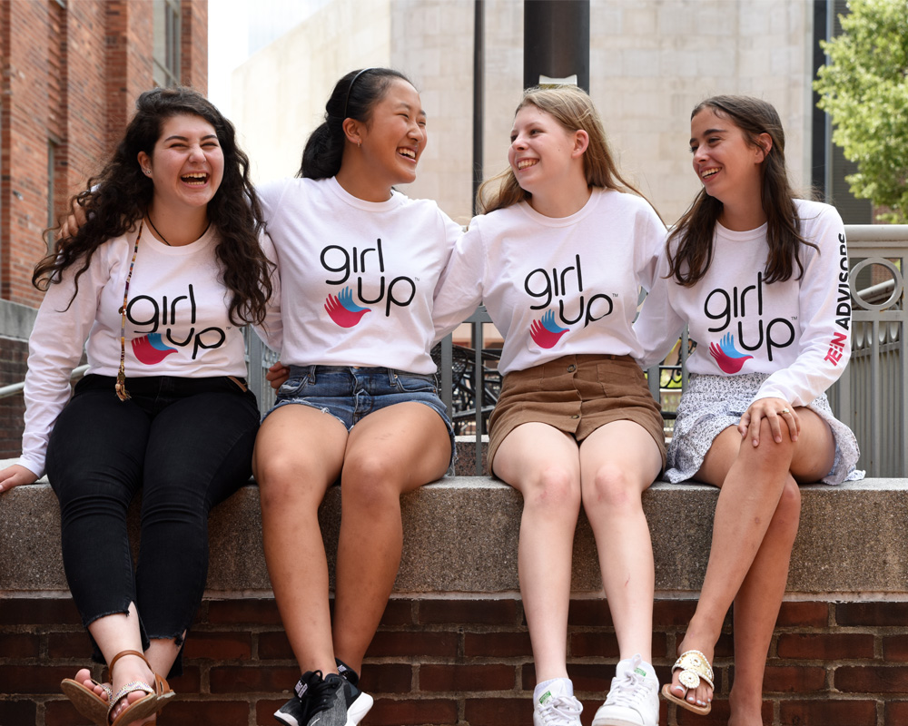 4 teen advisors girls have a hand around each other shoulder and laughing and looking at each other