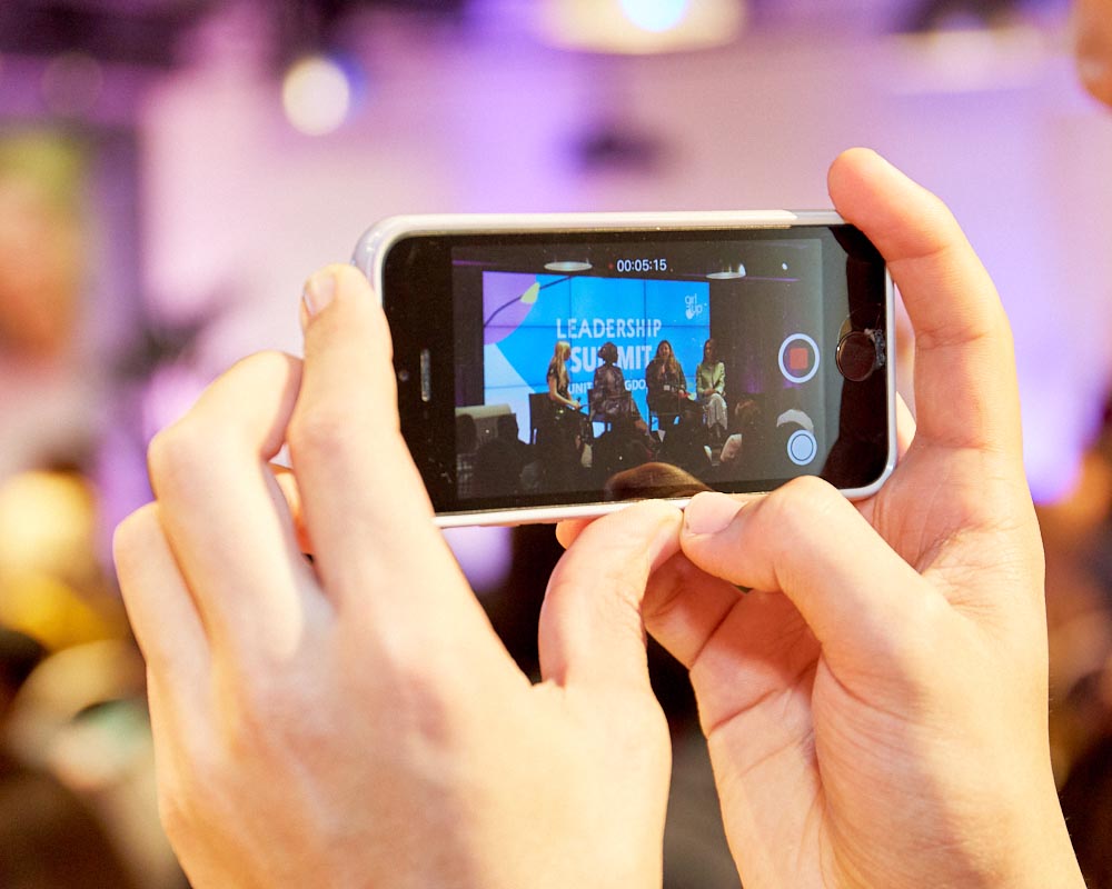 a head holding a iphone and recording on the phone of leadership summit speaking panel