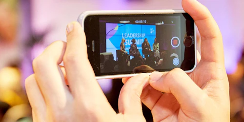 a head holding a iphone and recording on the phone of leadership summit speaking panel