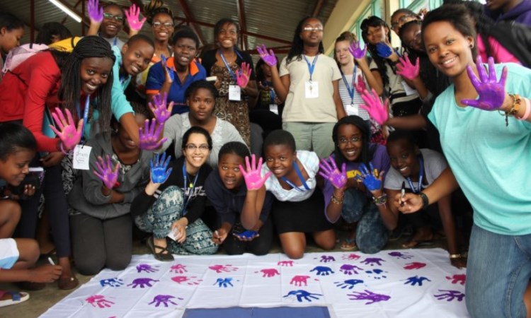 two girls are looking the laptop and researching and a lady is looking at what they see in the laptop