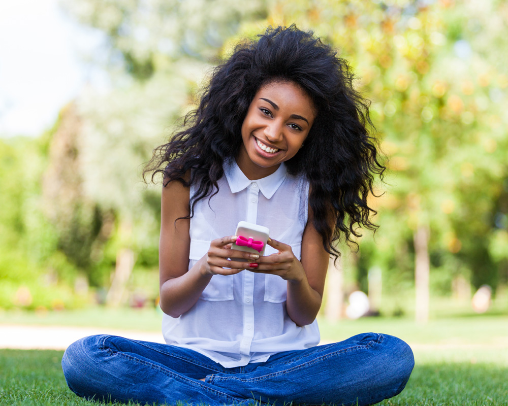 a girl with smile and looking straight and holding her iPhone