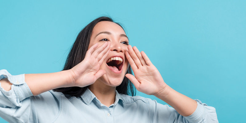 a girl with two hand next to her mouth with her mouth open, with blue background