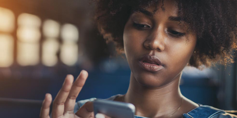 a girl who is looking down and using her finger to scrolling the phone