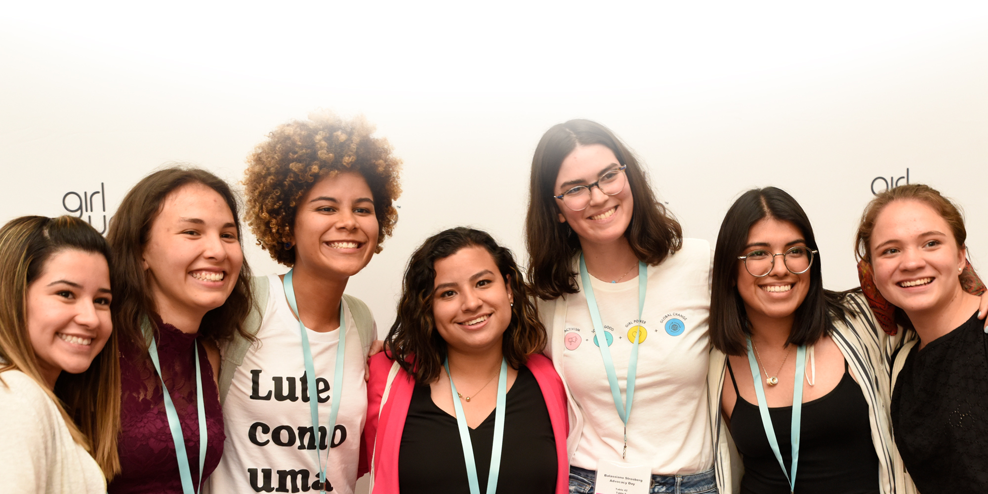 7 girls group picture smile and have their hand around each other back