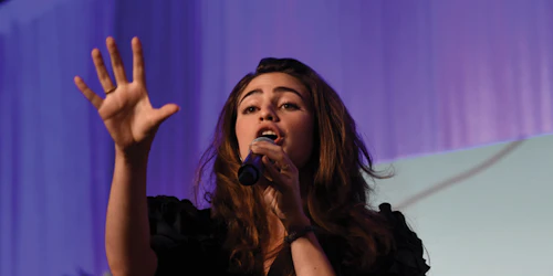 lower angle shot _ a girl holding a mic and have right hand open face toward to the front