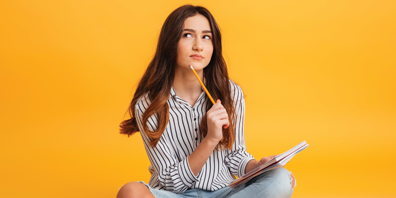a girl is holing a pen and looking up