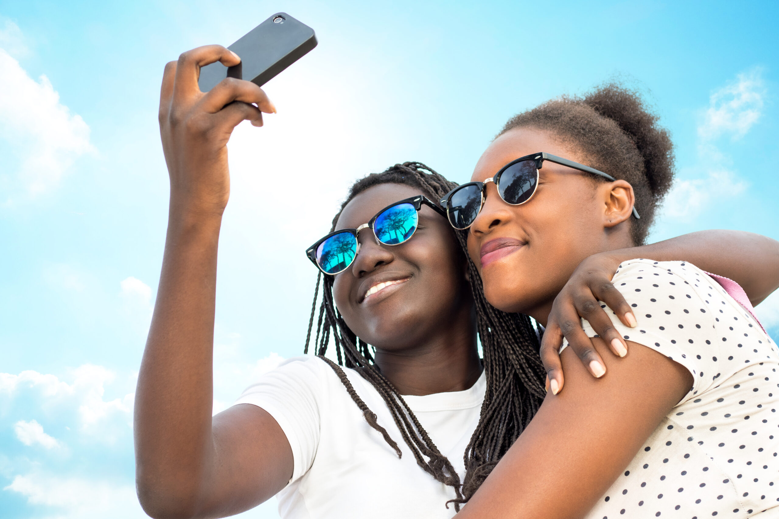Two girls hugging and taking a selfie outdoors